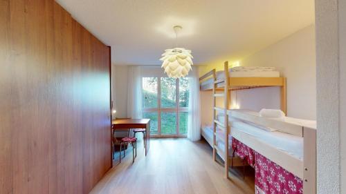 a room with two bunk beds and a desk at Ferienwohnung für 5 Personen Piz Linard Lantsch-Lenzerheide in Lenz