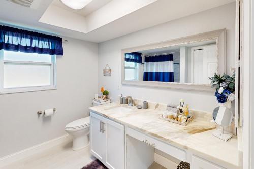 een badkamer met een wastafel, een toilet en een spiegel bij Morning Glory in Cape Coral