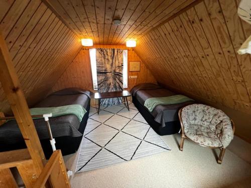 a attic room with two beds and a chair at Narikka Cottage, Cozy Stay in Central Kittilä, Near Levi Ski Resort in Kittilä