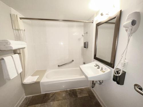 a white bathroom with a sink and a bath tub at Lincoln Hotel Monterey Park Los Angeles in Monterey Park