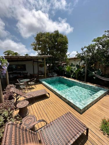 a pool on a wooden deck with chairs and a table at Pousada Ares de Noronha in Fernando de Noronha