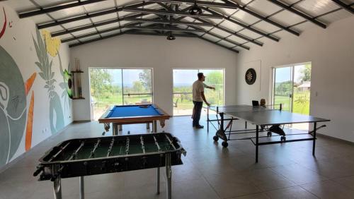 Un homme debout dans une pièce avec deux tables de ping-pong dans l'établissement Haasienda - Nido del Colibri - Casa de Arbol, 