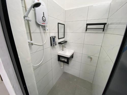 y baño blanco con lavabo y ducha. en Pagoh Town Homestay en Pagoh
