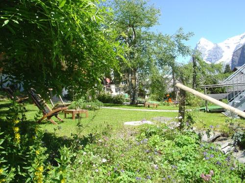 a garden with a table and benches and mountains at Hotel Blumental in Mürren