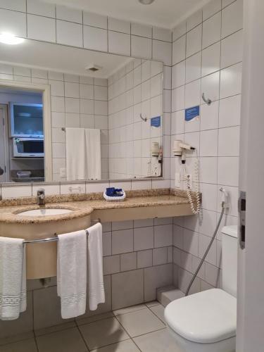 a bathroom with a sink and a toilet and a mirror at Jurerê Beach Village Studios Para Temporada in Florianópolis