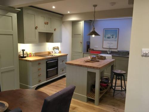 une cuisine avec des armoires blanches et une table en bois dans l'établissement St Anthony’s, bright perkily decorated 3 bedroom house, à Ampleforth