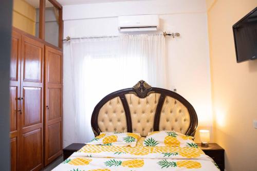 um quarto com uma cama com uma cabeceira em madeira e uma janela em Hypo Guest Lounge em Iaundé