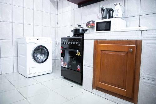 a kitchen with a stove and a washing machine at Hypo Guest Lounge in Yaoundé