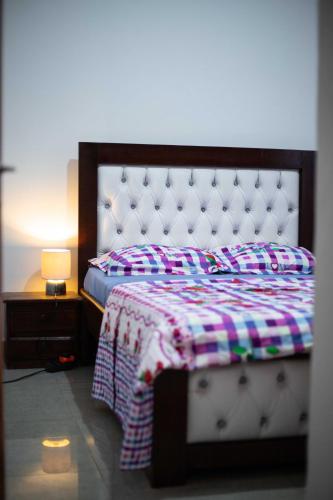 a bedroom with a bed and a nightstand with a lamp at Hypo Guest Lounge in Yaoundé