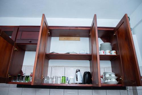 a kitchen cabinet with doors open with dishes at Hypo Guest Lounge in Yaoundé