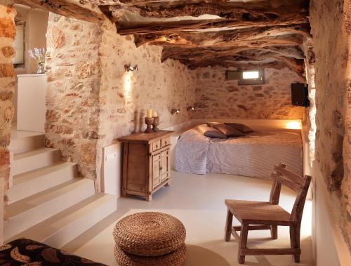 a bedroom with a bed and a chair and stairs at Themonies Luxury Suites in Chora Folegandros