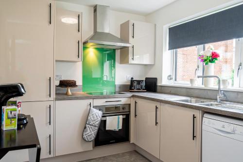 a kitchen with white cabinets and a green sink at 8 Beds, 3baths Perfect For Contractors & Teams in Basingstoke