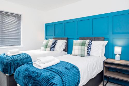two beds in a room with blue walls at 8 Beds, 3baths Perfect For Contractors & Teams in Basingstoke