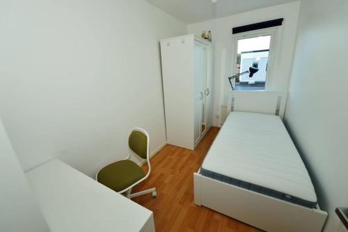 1 dormitorio con 1 cama, 1 silla y 1 ventana en Radhus med bekvämt läge en Täby