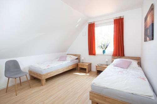 sypialnia z 2 łóżkami, krzesłem i oknem w obiekcie Ferienhaus Sturmmöwe Zingst w Zingst