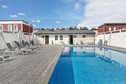 a large swimming pool with chairs on a wooden deck at Radhus med bekvämt läge in Täby