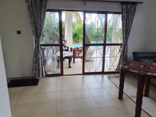uma sala de estar com uma porta que abre para um pátio em Diani Hideaway Beach Villa em Galu