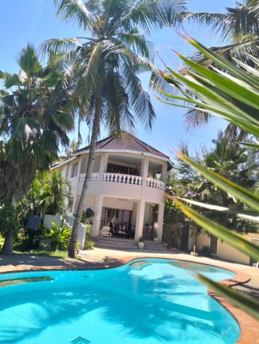 a villa with a swimming pool in front of a house at Diani Hideaway Beach Villa, private pool, air conditioning and WiFi in Galu