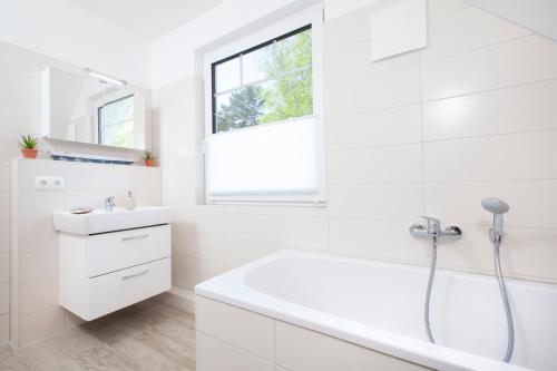 La salle de bains blanche est pourvue d'une baignoire et d'un lavabo. dans l'établissement Ferienhaus Sturmmöwe Zingst, à Zingst