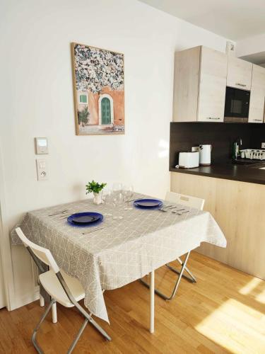 a dining room table with blue plates and chairs in a kitchen at Bright and fully renovated studio in Vanves in Vanves