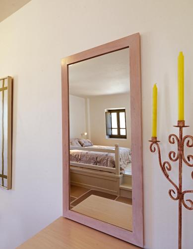 a mirror in a room with a bed and a candle at Themonies Luxury Suites in Chora Folegandros