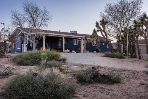 a blue house with trees and bushes in front of it at Wind Hill in Yucca Valley