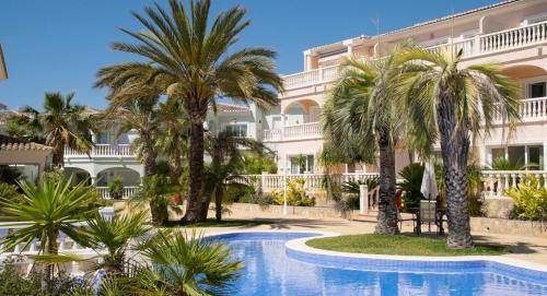 a hotel with palm trees and a swimming pool at Luxueus appartement aan de Costa Blanca in Benissa