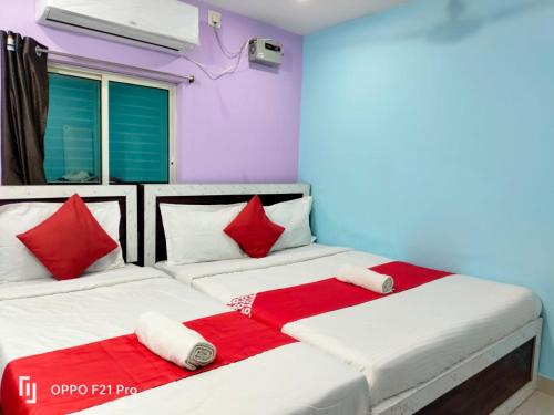 プリーにあるA1 ROOMS SEA GOLD ( COTTAGE) PURI BEACHのベッドルーム1室(ベッド2台、赤と白の枕付)