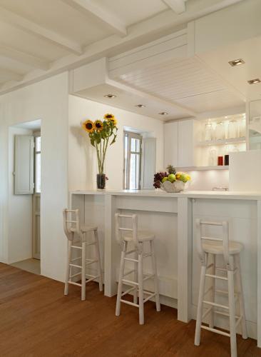 a kitchen with a white counter and stools at Themonies Luxury Suites in Chora Folegandros