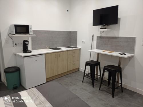 - une cuisine avec un évier et un bureau avec deux tabourets dans l'établissement Ravissant Studio, à Bétheniville