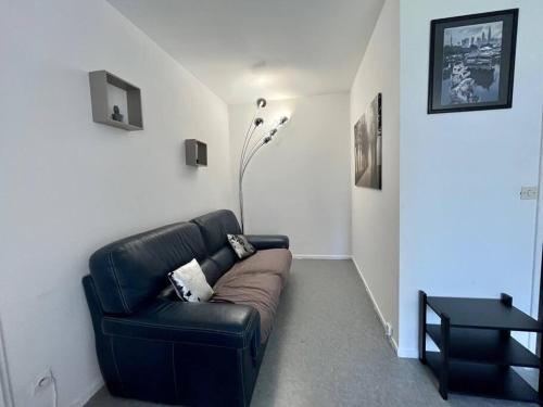 a living room with a black leather couch and a table at Lumineux F2 / Pkg gratuit / proche A31 in Metz