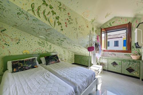Flora Cottage Guesthouse Burano في بورانو: غرفة نوم مع سرير مع زهور على الحائط