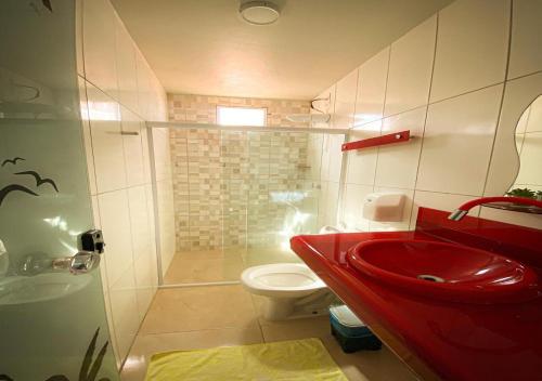 a bathroom with a red sink and a toilet at Flats Bahia in Coruripe