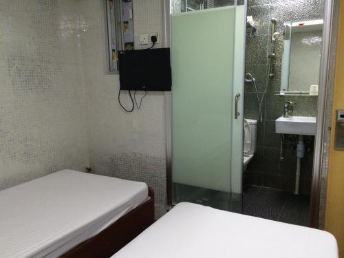 a small room with two beds and a bathroom at Jinhai Hotel in Hong Kong