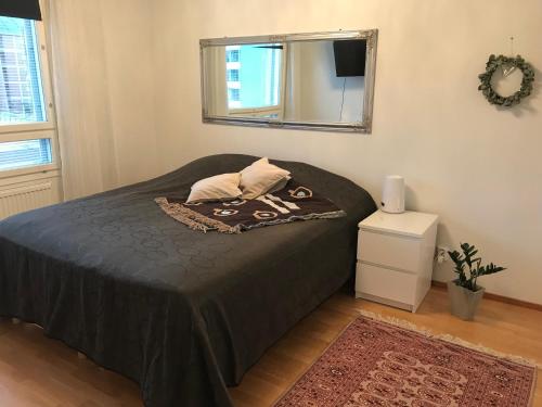 una camera da letto con un letto con copriletto nero e uno specchio di Ilmastoitu 55 m2 huoneisto saunalla Lahden satamassa a Lahti