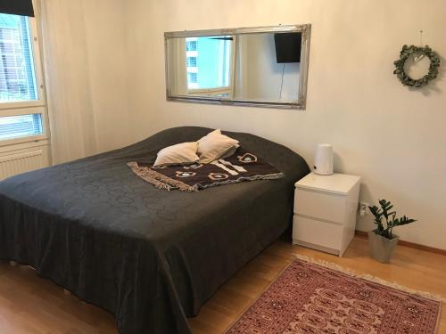 a bedroom with a bed with a black bedspread and a mirror at Ilmastoitu 55 m2 huoneisto saunalla Lahden satamassa in Lahti