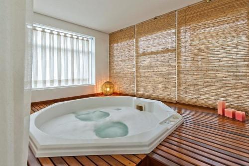 Suite executiva reformada dentro do hotel Radisson في ساو باولو: حوض استحمام كبير أبيض في غرفة مع نافذة