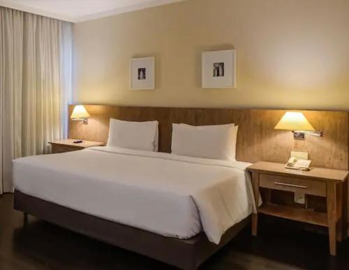 a large bed in a hotel room with two lamps at Suite executiva Park in Radisson Berrini Luxo Queen 17 in Sao Paulo