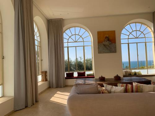 a living room with large windows and a couch at The Cliff Hotel. in Tel Aviv