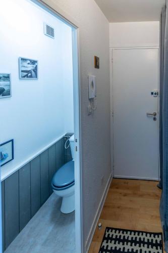 La salle de bains est pourvue de toilettes bleues et d'une porte. dans l'établissement LE PRIEURE, à Dinard