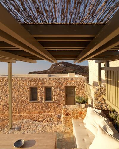 a building with a stone wall and a roof at Themonies Luxury Suites in Chora Folegandros