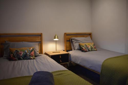 a bedroom with two beds and a lamp on a table at Yr Hen Beudy Barn Conversion Sleeps 4 Dogs Ok in Carmarthen