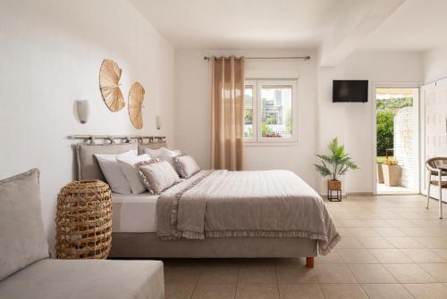 a white bedroom with a bed and a tv at Anastasia Mare Studios in Pefkochori