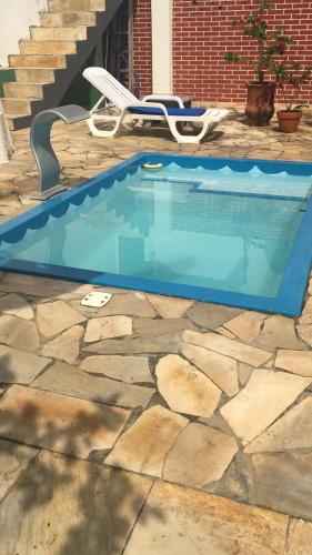 una piscina en un patio con una silla y escaleras en Saquarema hospedagem en Saquarema