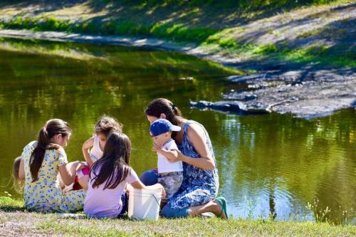 a group of girls sitting on the grass near a pond at Pinecraft Blue Heron Tiny Home in Sarasota