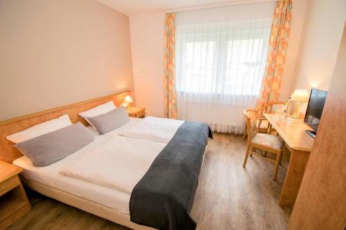 a hotel room with a bed and a desk at Landhotel Ringelsteiner Mühle in Moselkern