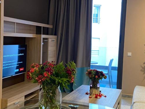 two vases with flowers on a table in a living room at Atlas-Résidence by Rent-Inn in Rabat