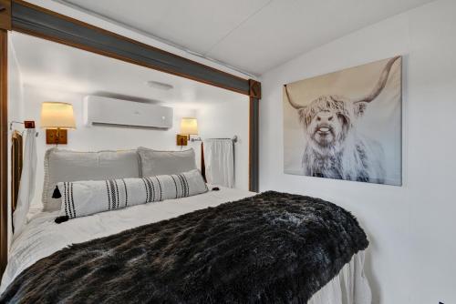 a bedroom with a bed with a picture of a cow on the wall at Lucinda Luxury RV with Hot Tub in Fredericksburg