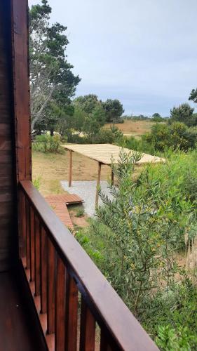 a wooden balcony with a picnic table in a field at Nairandey in La Pedrera