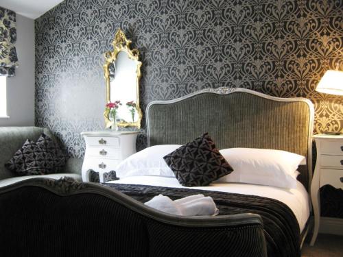 a bedroom with a bed with a chair and a mirror at Holly Tree B&B in Bromyard